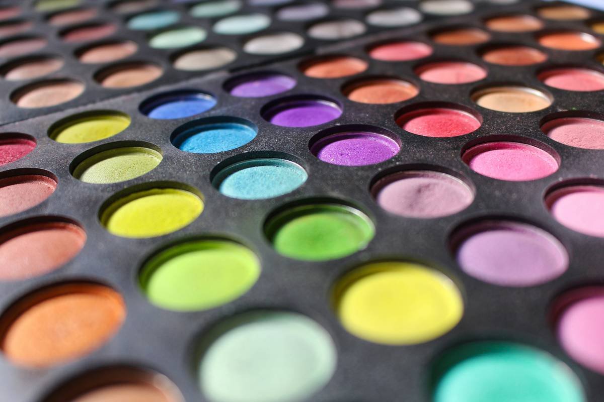 Side-by-side swatches showing high-pigment vs. low-pigment colorful makeup palettes on skin